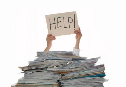 A person holding up a sign in front of a pile of papers.